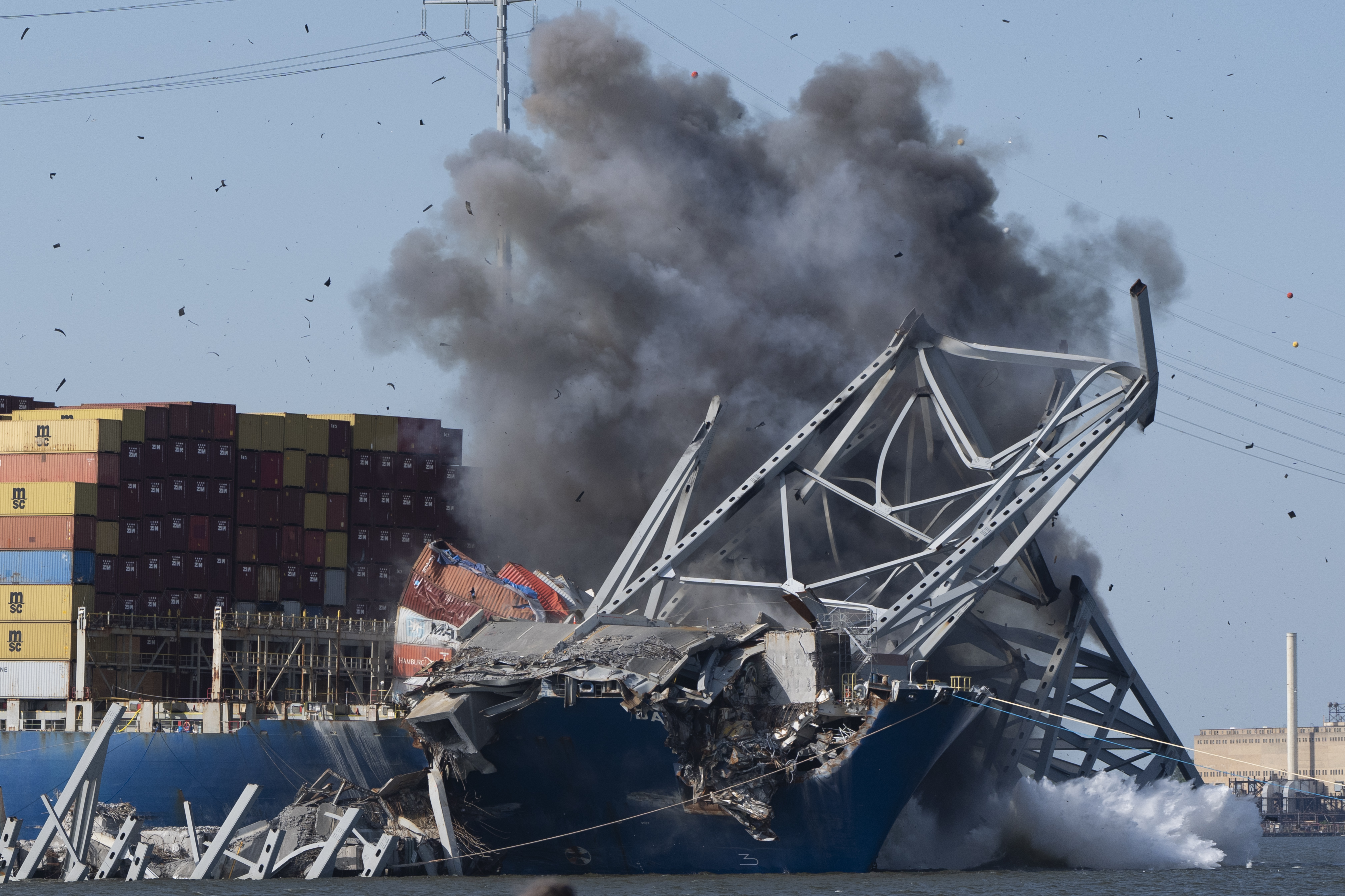 Explosive charges are detonated to bring down sections of the collapsed Francis Scott Key Bridge resting on the container ship Dali on Monday, May 13, 2024, in Baltimore. (AP Photo/Mark Schiefelbein)